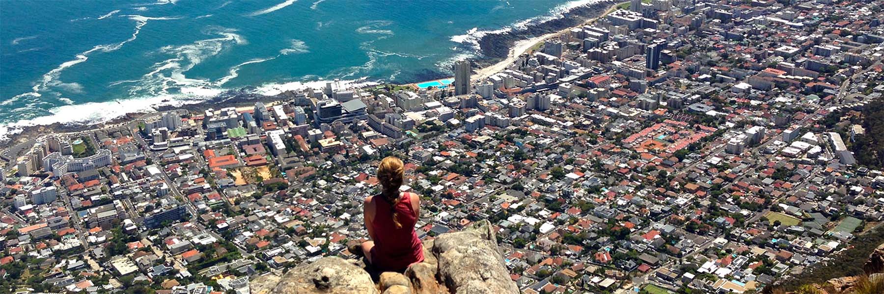 woman sitting atop mountain overlooking Cape Town city